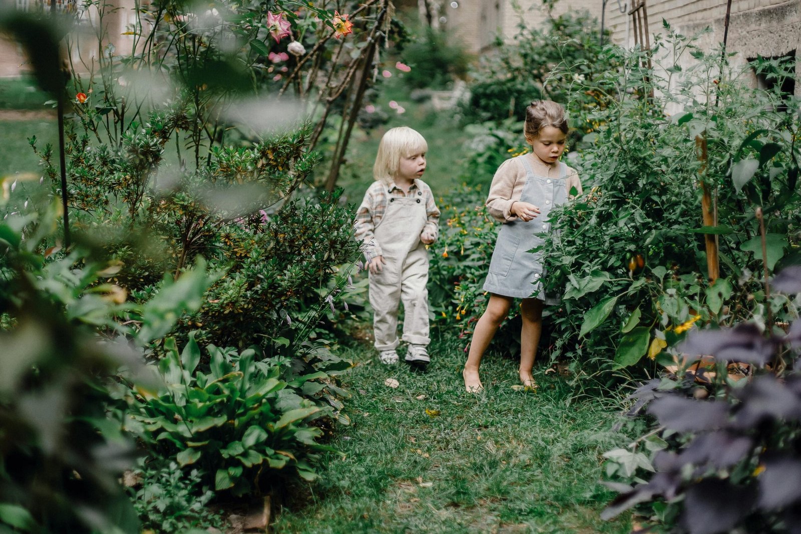two children standing in a garden with flowers