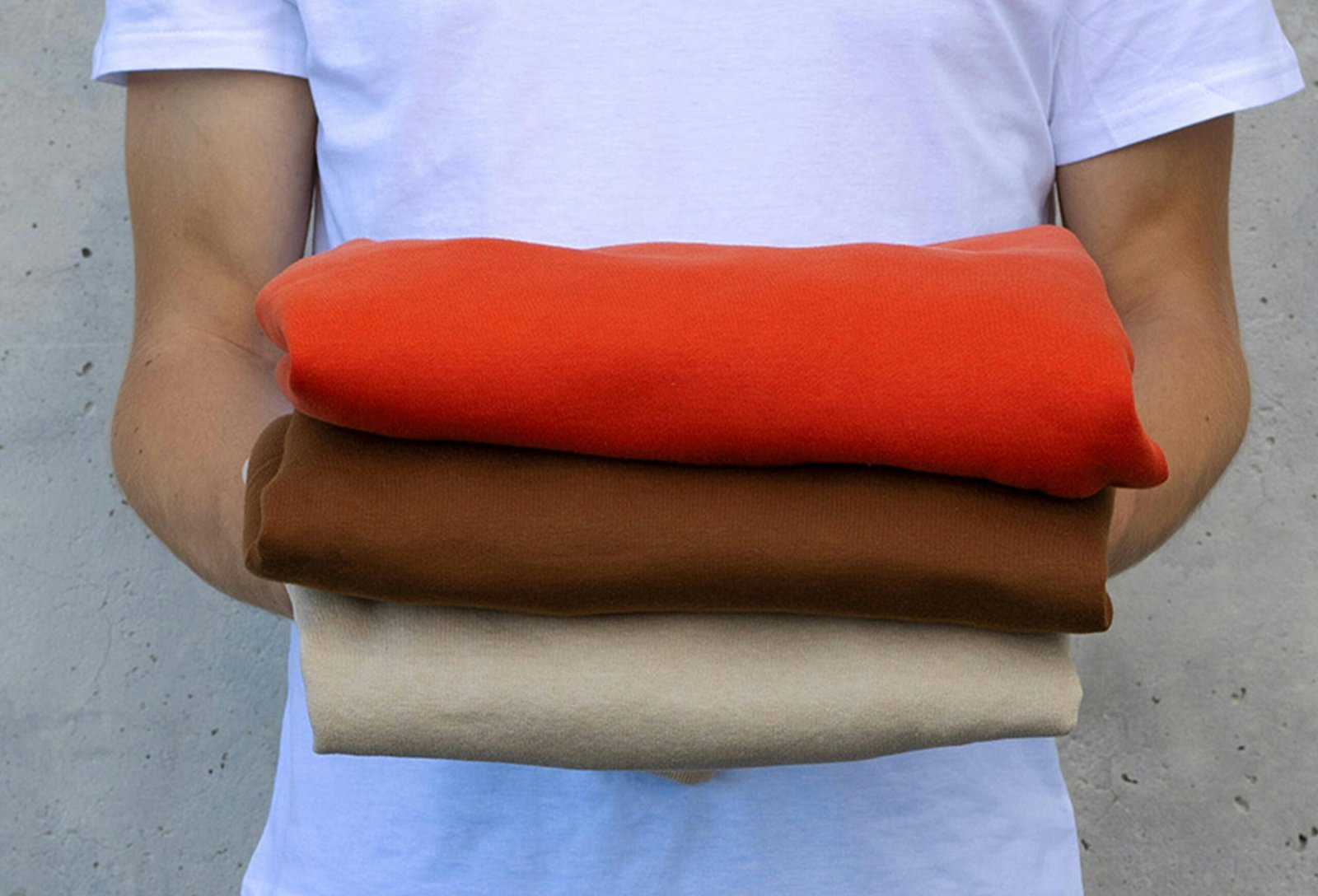 a man holding a stack of four different colored fabrics