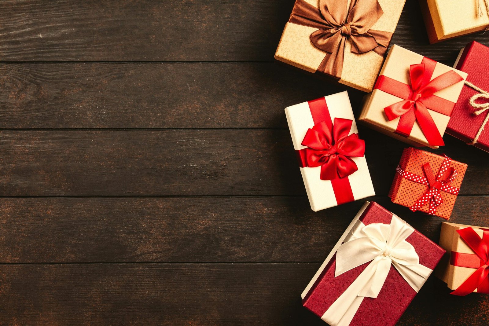 a bunch of gift boxes with bows on a wooden table