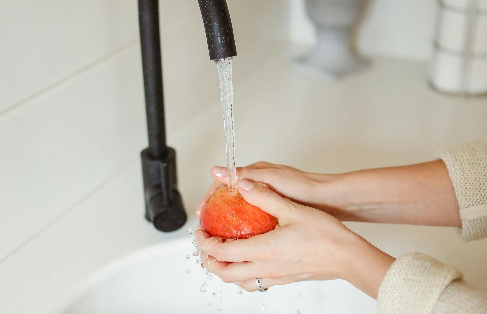 a person washing a red apple in their hand