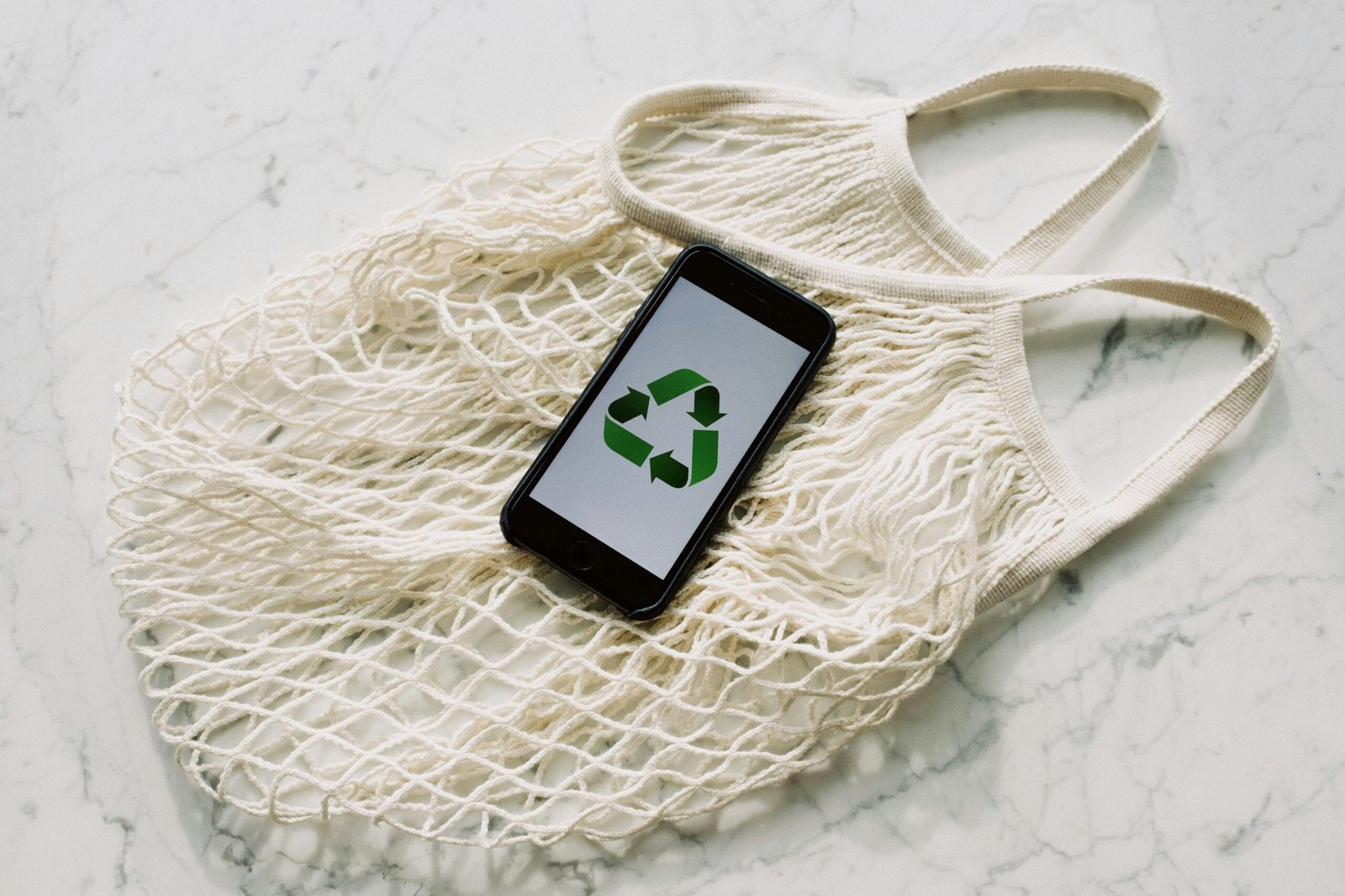 a cell phone with recycle logo on top of a net bag