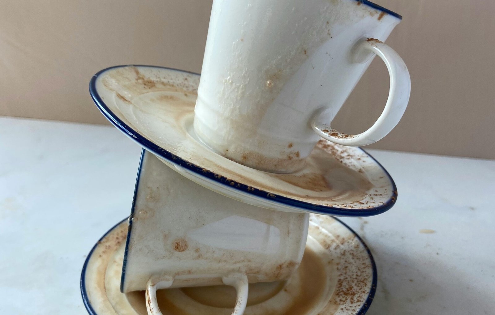 a stack of dishes with a cup of coffee and a mug