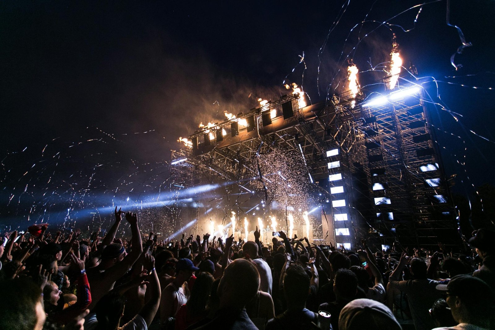 a crowd of people standing in front of a stage with fireworks